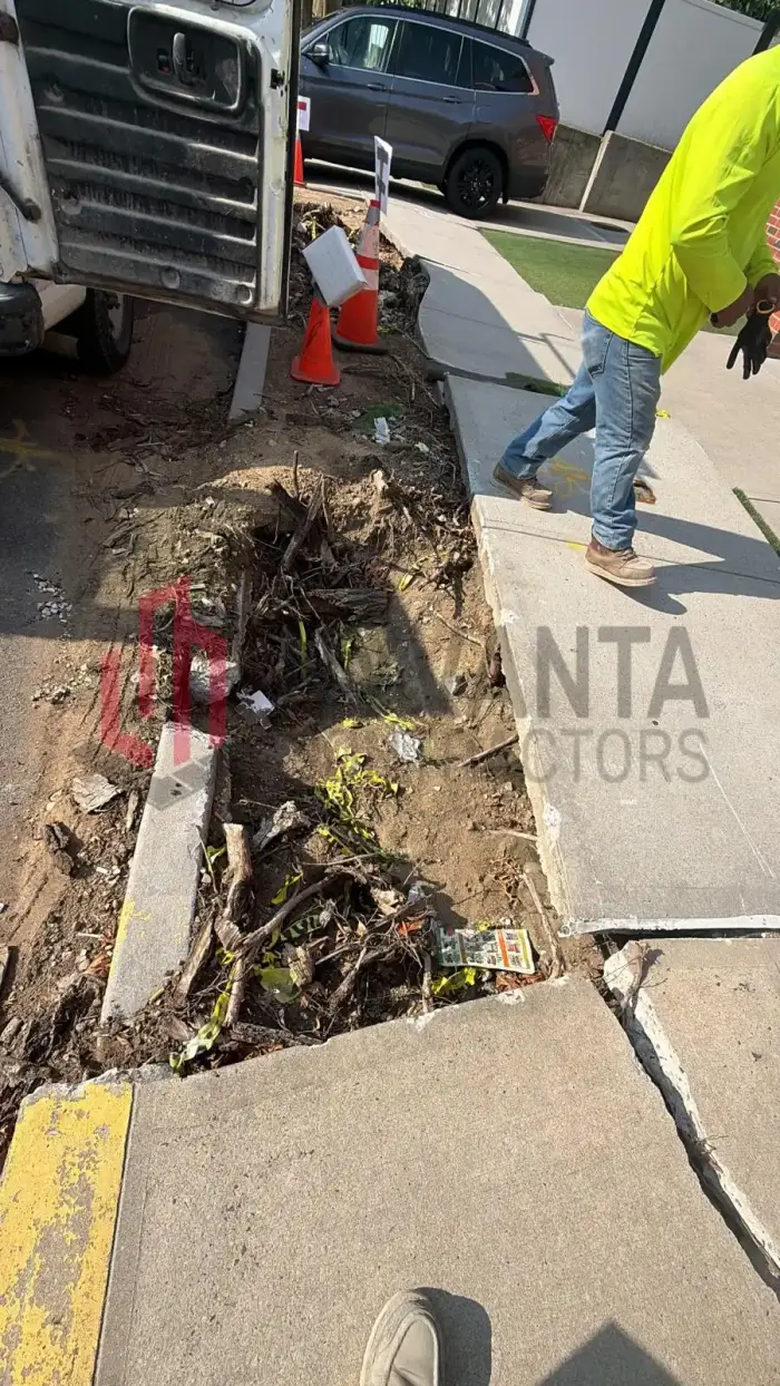 Deteriorated sidewalk flags saw-cut and broken out, exposing the base beneath